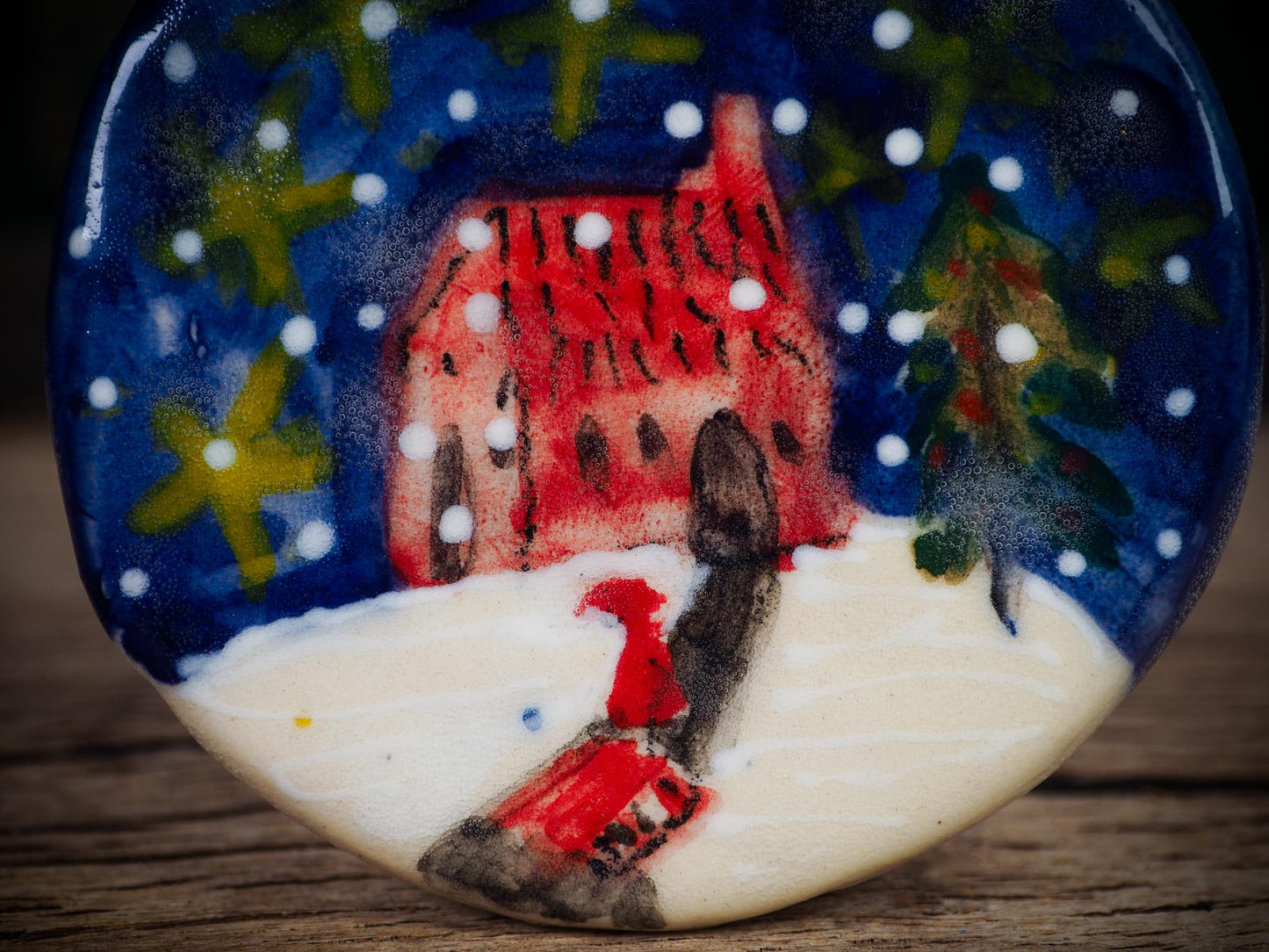 Handmade ceramic winter night ornament with red house, snowy scene, and painted stars, created by Idania Salcido aka Danita Art for Christmas decorating or gifting.