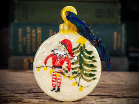 Handmade ceramic elf ornament with tree and holiday lights, created by Idania Salcido aka Danita Art for Christmas decorating or gifting.