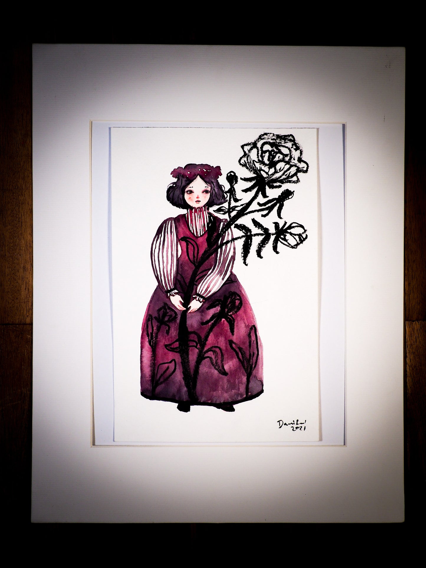 An original mixed media watercolor by Idania Salcido, the artist behind Danita Art. This is a beautiful watercolor painting, A girl wearing a crimson red dress with a huge black ink and watercolor rose flower in her hands. Painted with watercolors over watercolor paper.