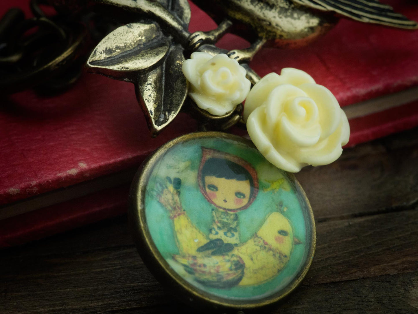 A yellow bird, yellow roses and brass leaves decorate a handmade original creation in mixed media jewelry necklace art by Danita