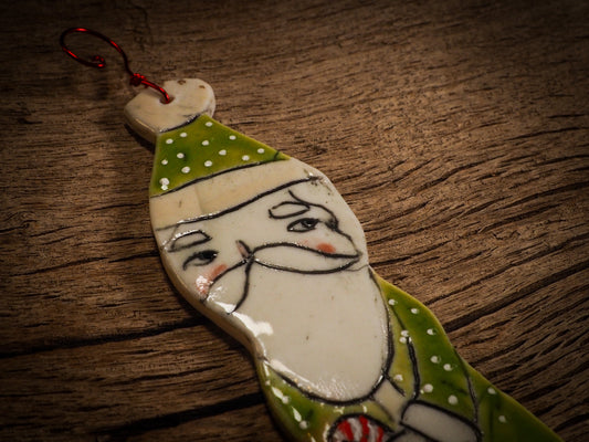 An original Christmas Holiday tree round glazed ceramic ornament handmade by Idania Salcido, the artist behind Danita Art. Glazed carved sgraffito stoneware, hand painted and decorated, it is illustrated by hand with snowmen, Christmas trees, Santa Claus, angels and snow balls and winter themes.