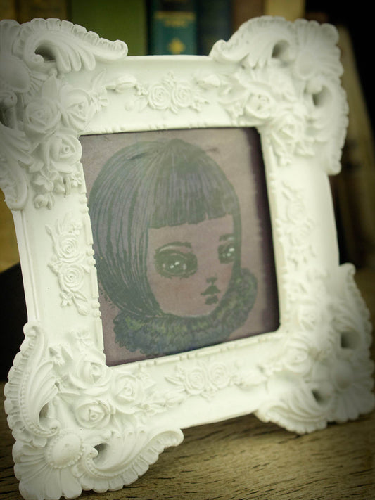 This is an original ink drawing by Danita Art, made on paper with a scratch pen and finished in watercolor. It arrives in a beautiful white frame with roses in the side that contrast with the darkness of the original painting.