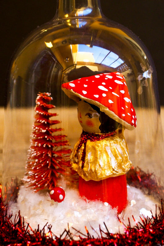 An original handmade christmas tree ornament by Idania Salcido. A clear domed diorama with a holiday scene with Santa Claus elves, Christmas Trees, Elves, Gifts and magical glitter deer.