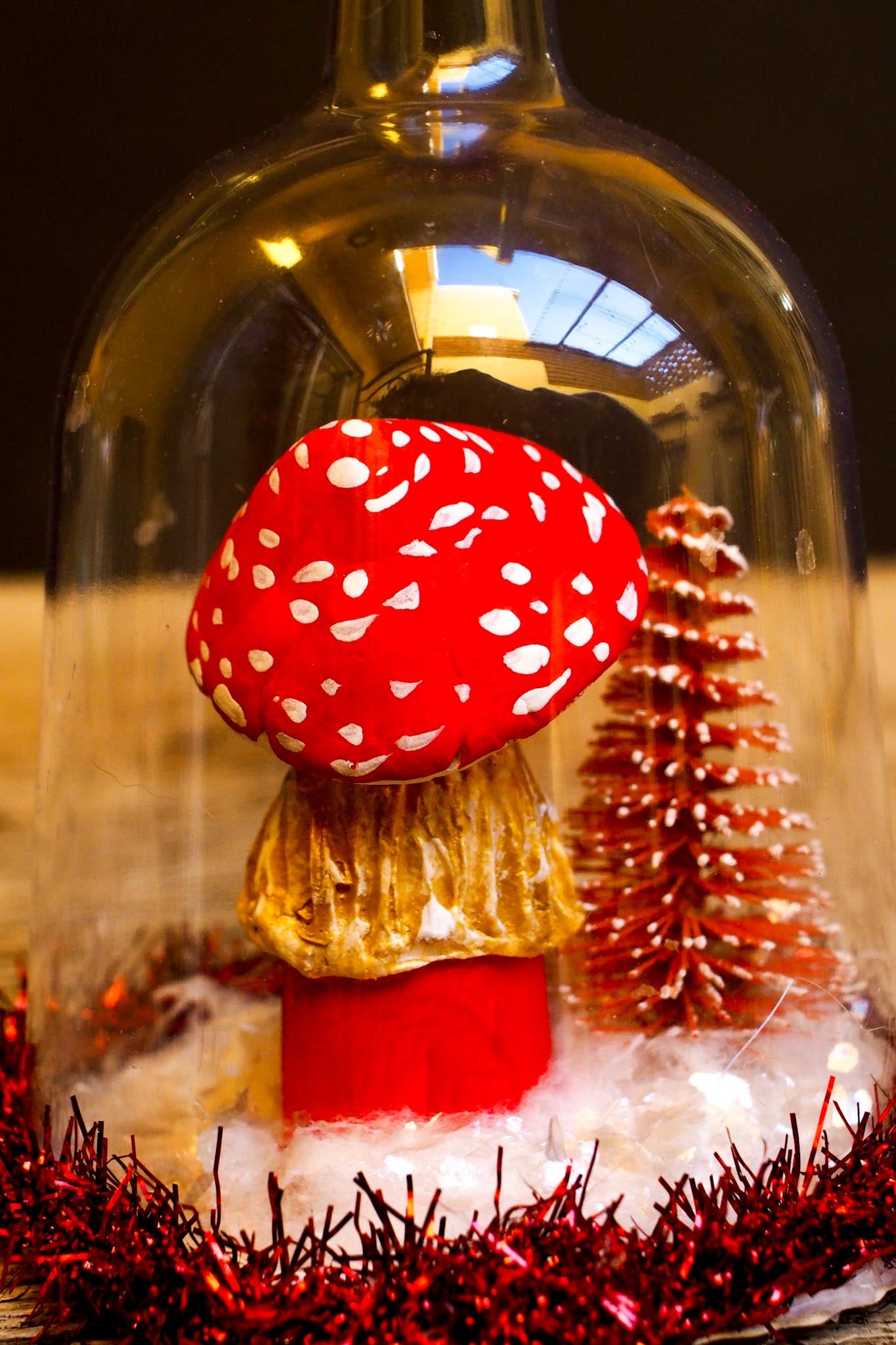 An original handmade christmas tree ornament by Idania Salcido. A clear domed diorama with a holiday scene with Santa Claus elves, Christmas Trees, Elves, Gifts and magical glitter deer.