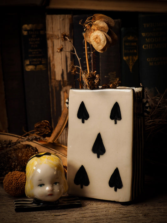 five of spades card glazed ceramic figure inspired by Alice in Wonderland made by Idania Salcido, the mixed media artist and ceramist behind Danita Art. Earth clay is hand sculpted and glazed and kiln fired to create a ceramic home decor heirloom figurine. Each unique art piece is a one of a kind fine pottery artwork.