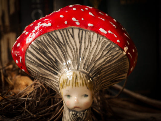 red toadstool mushroom fungi glazed ceramic torso figure inspired by Alice in Wonderland by Idania Salcido, the artist behind Danita Art. Lumps of clay hand sculpted and glazed are kiln fired. Beautiful fungi shaped wall hangings with nail hole in the back to place on wall with a hook or display on shelf or showcase.