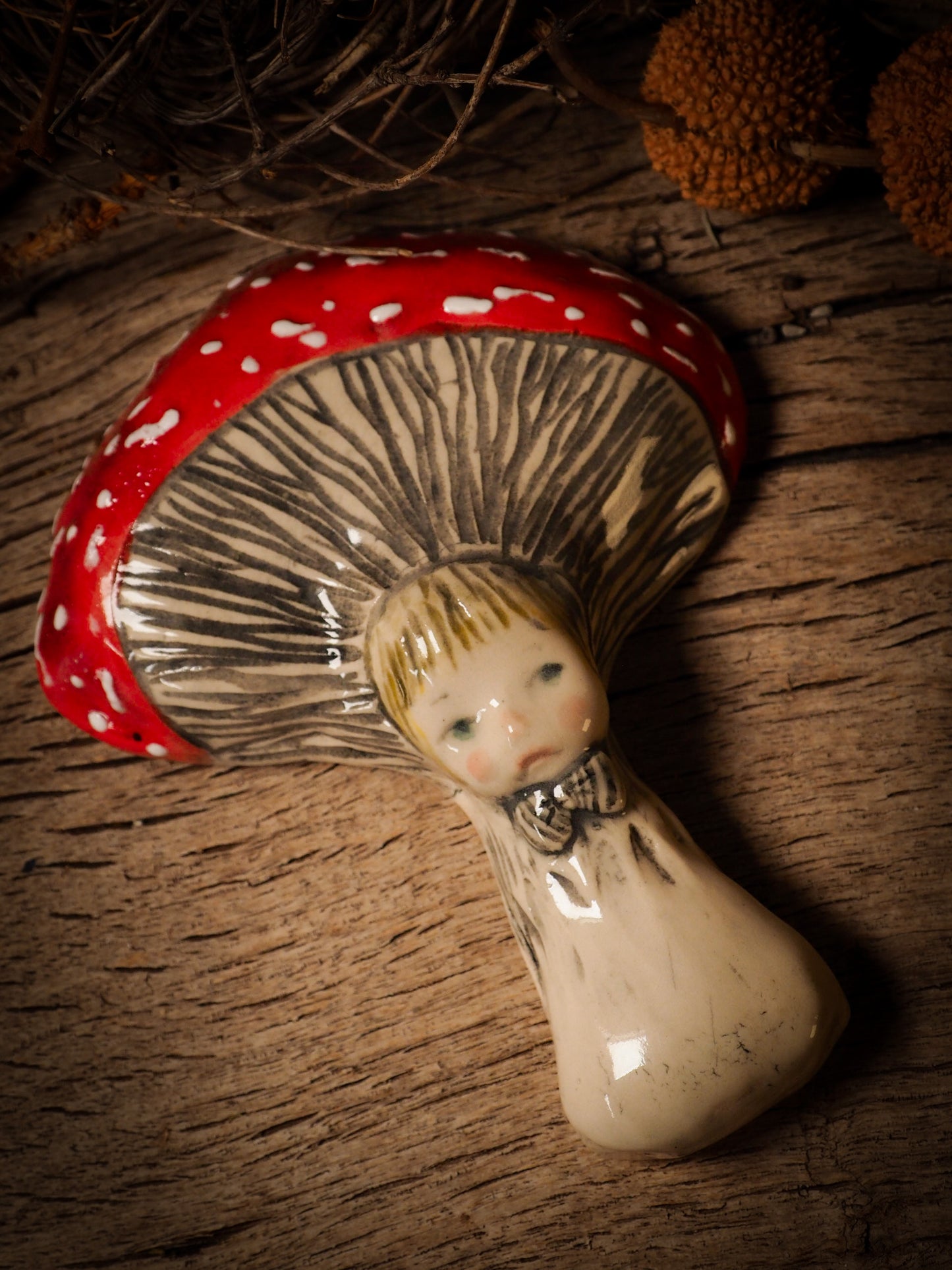 red toadstool mushroom fungi glazed ceramic torso figure inspired by Alice in Wonderland by Idania Salcido, the artist behind Danita Art. Lumps of clay hand sculpted and glazed are kiln fired. Beautiful fungi shaped wall hangings with nail hole in the back to place on wall with a hook or display on shelf or showcase.