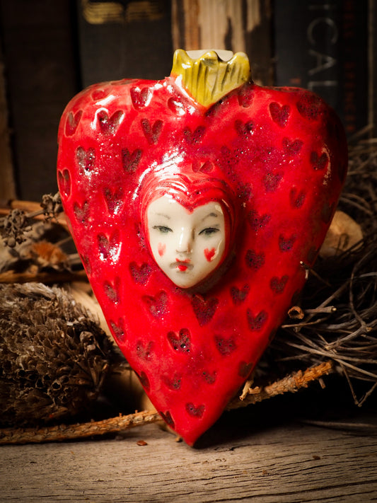 red burning heart glazed ceramic torso figure inspired by Alice in Wonderland by Idania Salcido, the artist behind Danita Art. Lumps of clay hand sculpted and glazed are kiln fired. Beautiful heart shaped wall hangings with nail hole in the back to place on wall with a hook or display on shelf or showcase.