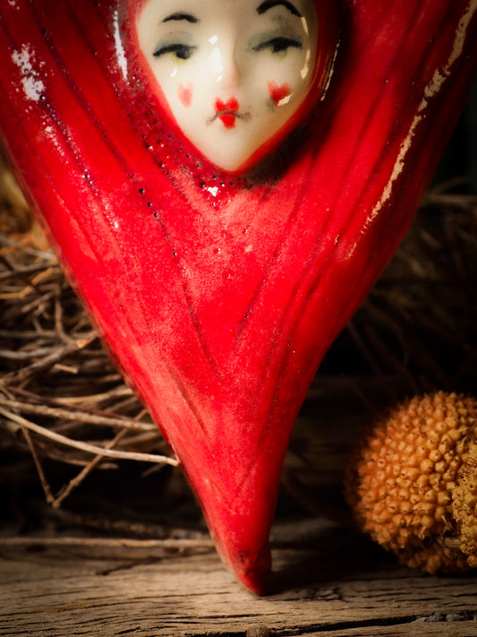 red burning heart glazed ceramic torso figure inspired by Alice in Wonderland by Idania Salcido, the artist behind Danita Art. Lumps of clay hand sculpted and glazed are kiln fired. Beautiful heart shaped wall hangings with nail hole in the back to place on wall with a hook or display on shelf or showcase.