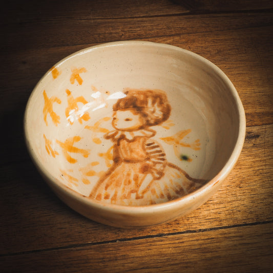 An original Idania Salcido Danita Art ceramic cat pet food plate. Handmade from stoneware, this glazed ceramics one of a kind artwork is perfect for any kitchen plate and bowls unique collection. Thumbprints and intentionally irregular shape give the bowl a cozy, warmly familiar feel when you pick it. A flock of yellow birds greets a beautiful girl in a striped dress, painted in watercolor style underglaze by Danita Art.