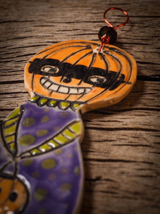 An original handmade Halloween ornament by Idania Salcido, Danita Art. Each ornament is hand carved with pumpkins, witches, cats, jack-o-lanterns and moons. Made with fired glazed ceramics, this little witch, jack-o-lantern and cat is carved with delicate patterns that make each ornament a one of a kind work of art.