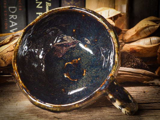 Fire glazed ceramic coffee mug by Idania Salcido, Danita Art. On Halloween, Danita creates ceramic containers for pumpkin spice coffee, warm tea or sweets to give on trick-or-treat night. With carved with Halloween ghosts, skeletons, witches, ghouls, black cats, jack-o-lanterns, item is food safe, hand wash only.