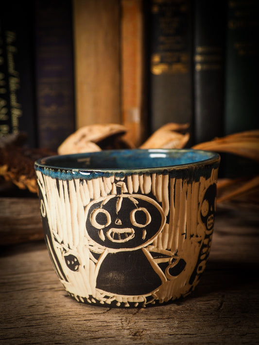 Fire glazed ceramic coffee mug by Idania Salcido, Danita Art. On Halloween, Danita creates ceramic containers for pumpkin spice coffee, warm tea or sweets to give on trick-or-treat night. With carved with Halloween ghosts, skeletons, witches, ghouls, black cats, jack-o-lanterns, item is food safe, hand wash only.