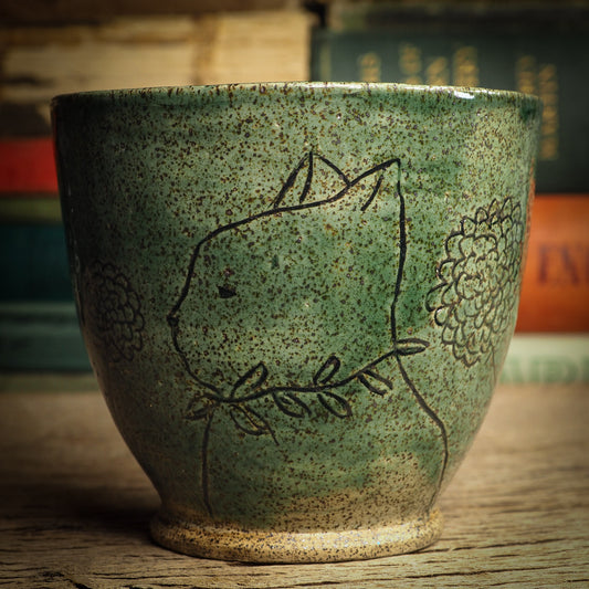 An original glazed ceramic mug by Idania Salcido, the artist behind Danita Art. It measures 4 x 4 x 3.5 Inches, with deep green hue glazes and hand decorated figures on the sides. Totally handmade in my studio, this is a unique piece that cannot be repeated. Food and drink safe, hand wash only.