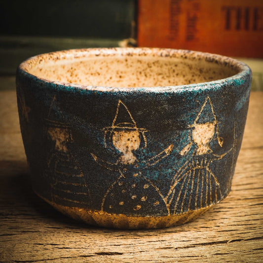 This little handmade ceramic halloween bowl by Idania Salcido Daita art has three witches carved on it, they are ready to cast a spell during a dark starry night, and you can see the magic stream from their wands in subtle bands of color across the deep, midnight blue sky. And of course, the moon and stars are there with them.