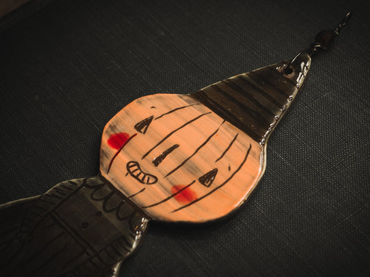 An original handmade Halloween ornament by Idania Salcido, Danita Art. Each ornament is hand carved with pumpkins, witches, cats, jack-o-lanterns and moons. Made with fired glazed ceramics, this little witch, jack-o-lantern and cat is carved with delicate patterns that make each ornament a one of a kind work of art.