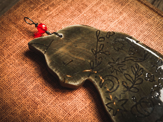 An original handmade Halloween ornament by Idania Salcido, Danita Art. Each ornament is hand carved with pumpkins, witches, cats, jack-o-lanterns and moons. Made with fired glazed ceramics, this little witch, jack-o-lantern and cat is carved with delicate patterns that make each ornament a one of a kind work of art.