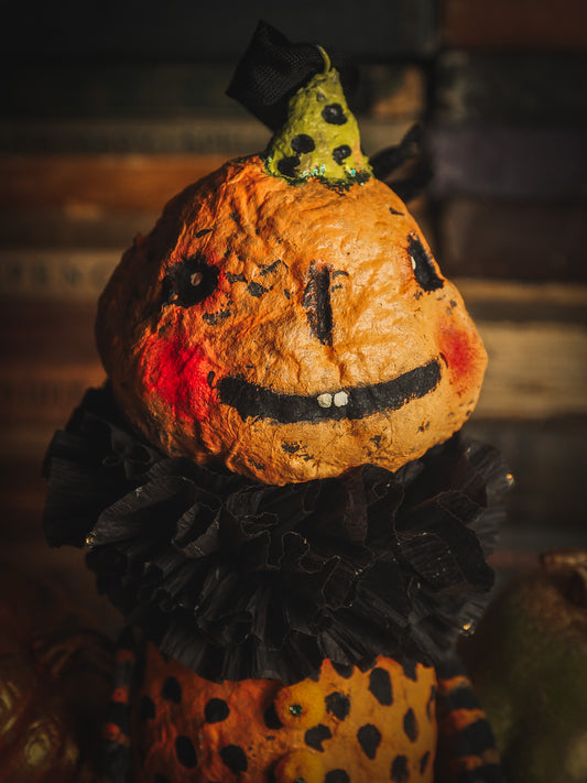 This adorable Halloween handmade ornament pumpkin jack-o-lantern doll monster by Idania Salcido, the artist behind Danita Art, is made with painted spun cotton and paper. It has hand painted face, teeth and eyes with a glittery paper had and matching paper costume. A Halloween home decoration on trick-or-treat night.