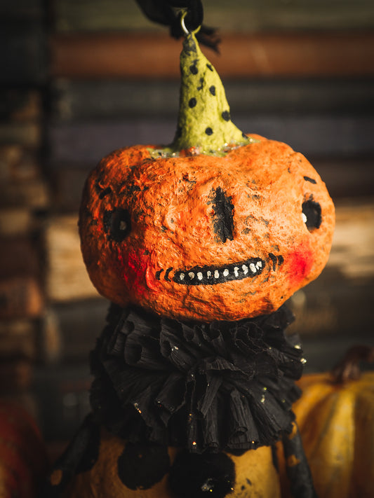 This adorable Halloween handmade ornament pumpkin jack-o-lantern doll monster by Idania Salcido, the artist behind Danita Art, is made with painted spun cotton and paper. It has hand painted face, teeth and eyes with a glittery paper had and matching paper costume. A Halloween home decoration on trick-or-treat night.