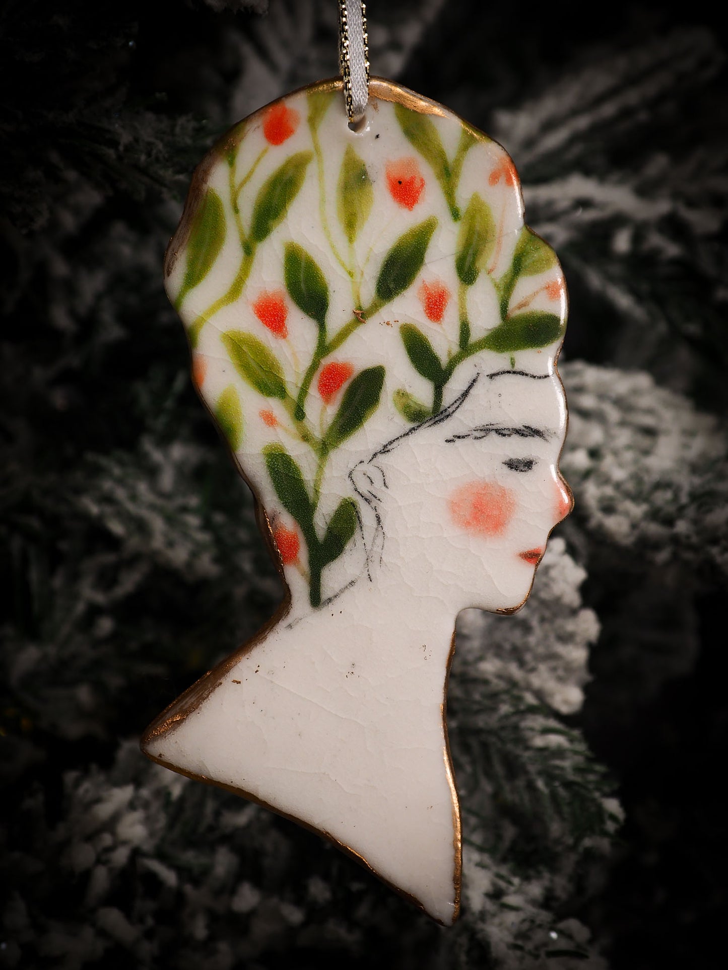 An original Christmas Holiday tree round glazed ceramic hanging ornament handmade by Idania Salcido, the artist behind Danita Art. Glazed carved sgraffito stoneware, hand painted and decorated, it is illustrated by hand with flowers, hearts, leaves, nature patterns and the face of Frida Kahlo.