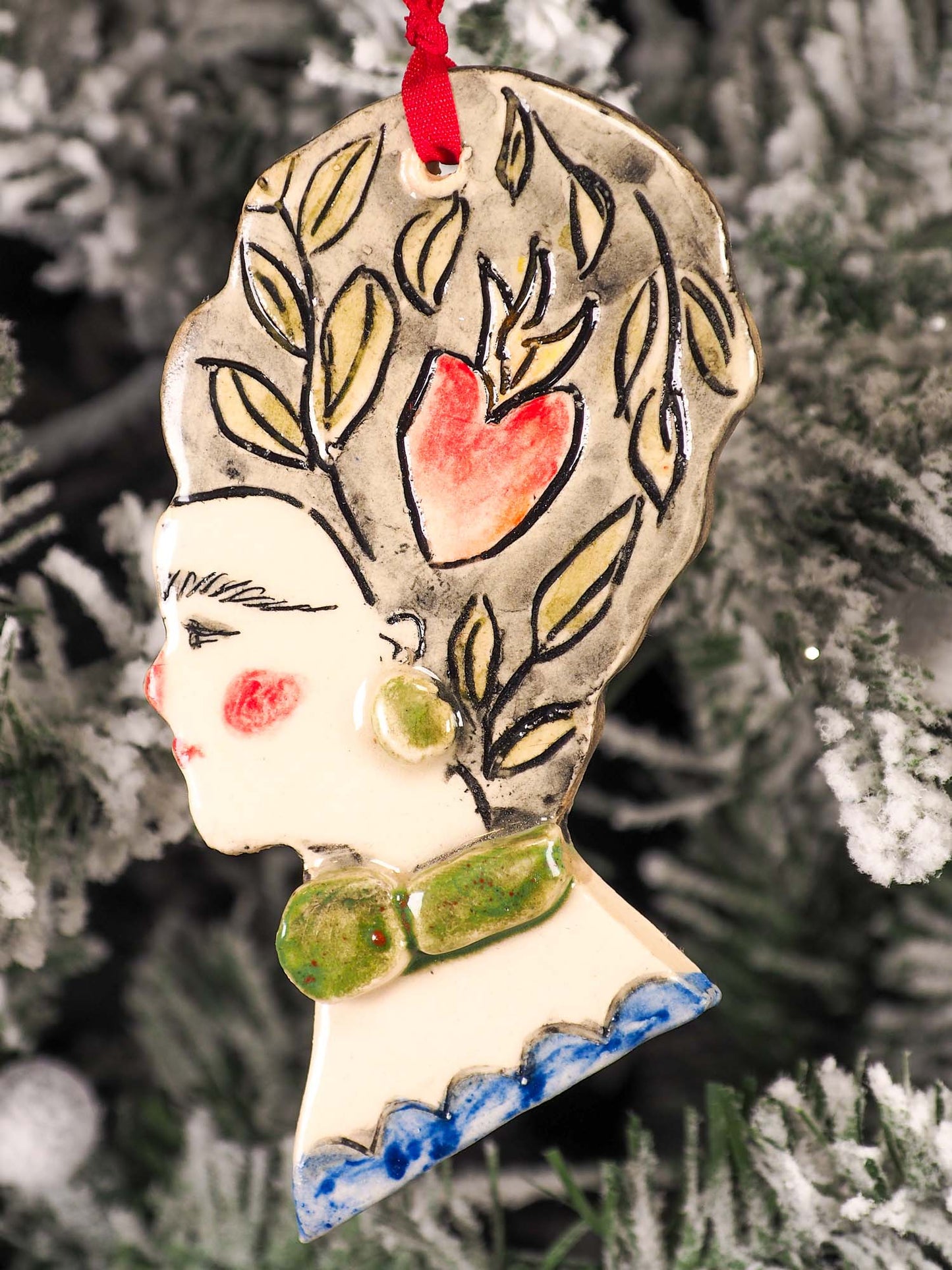 An original Christmas Holiday tree round glazed ceramic hanging ornament handmade by Idania Salcido, the artist behind Danita Art. Glazed carved sgraffito stoneware, hand painted and decorated, it is illustrated by hand with flowers, hearts, leaves, nature patterns and the face of Frida Kahlo.