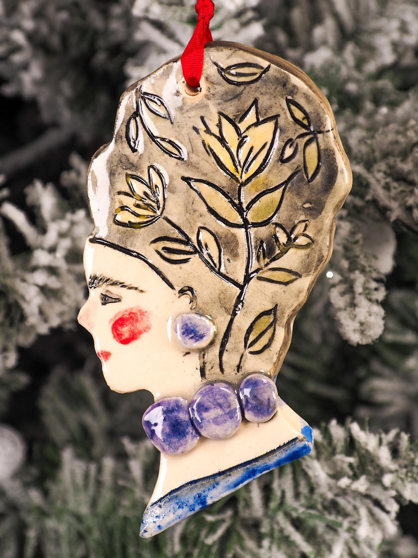 An original Christmas Holiday tree round glazed ceramic hanging ornament handmade by Idania Salcido, the artist behind Danita Art. Glazed carved sgraffito stoneware, hand painted and decorated, it is illustrated by hand with flowers, hearts, leaves, nature patterns and the face of Frida Kahlo.
