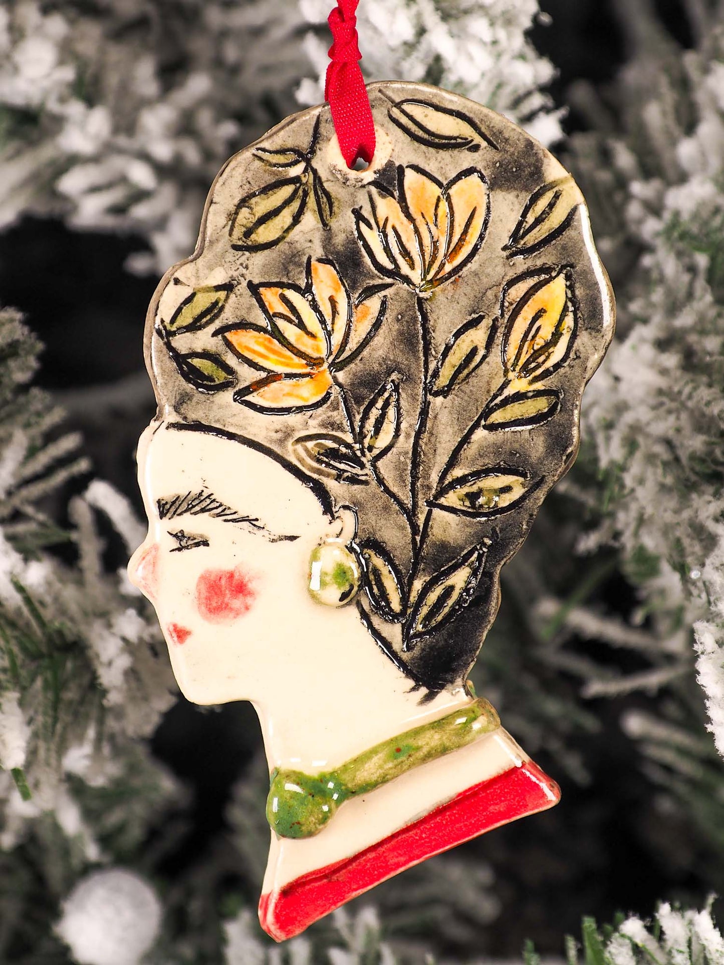 An original Christmas Holiday tree round glazed ceramic hanging ornament handmade by Idania Salcido, the artist behind Danita Art. Glazed carved sgraffito stoneware, hand painted and decorated, it is illustrated by hand with flowers, hearts, leaves, nature patterns and the face of Frida Kahlo.