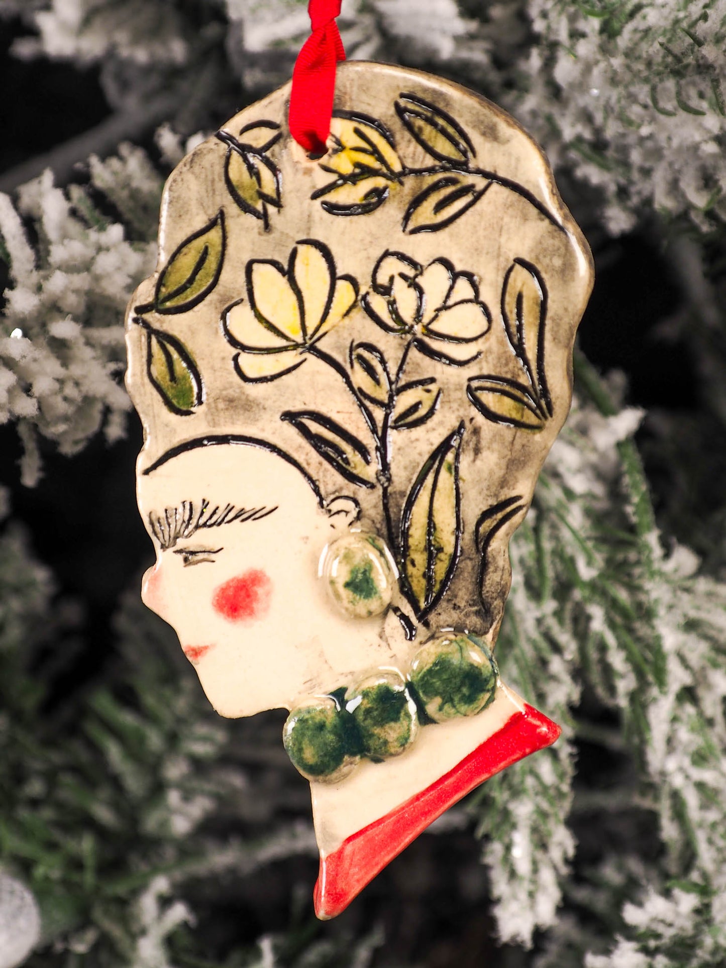 An original Christmas Holiday tree round glazed ceramic hanging ornament handmade by Idania Salcido, the artist behind Danita Art. Glazed carved sgraffito stoneware, hand painted and decorated, it is illustrated by hand with flowers, hearts, leaves, nature patterns and the face of Frida Kahlo.