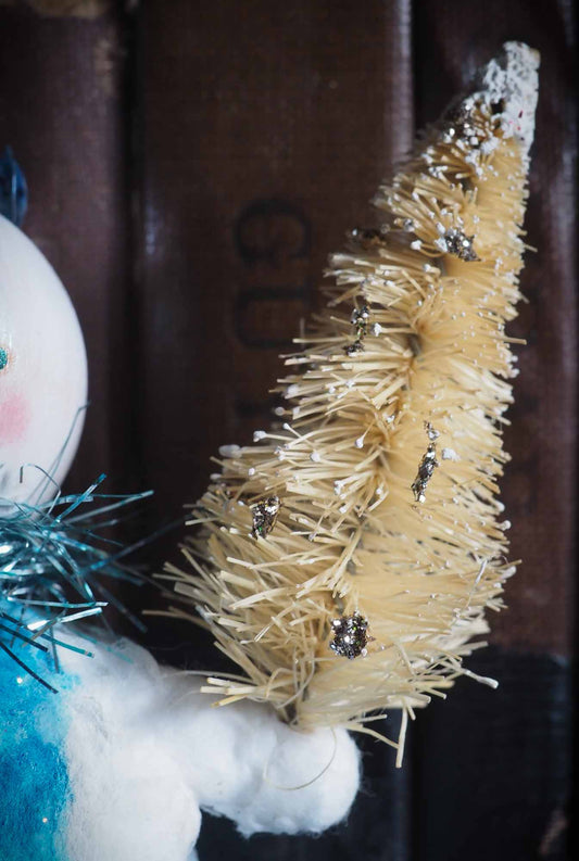 Spun cotton hand made ornament snowman by Danita Art. Made with organic cotton, painted in a vintage, folk art weathered style resembling Christmas tree handmade decorations from 19th century. Has bristle bottle brush tree, and decorative accents with glitter. Ready to hang on vintage tinsel ribbon on Christmas tree.