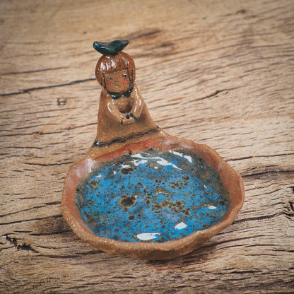 An original handmade ceramic girl with a bird on her head by Idania Salcido AKA Danita Art. She is perfect for storing jewelry, rings, and keys in her blue tray