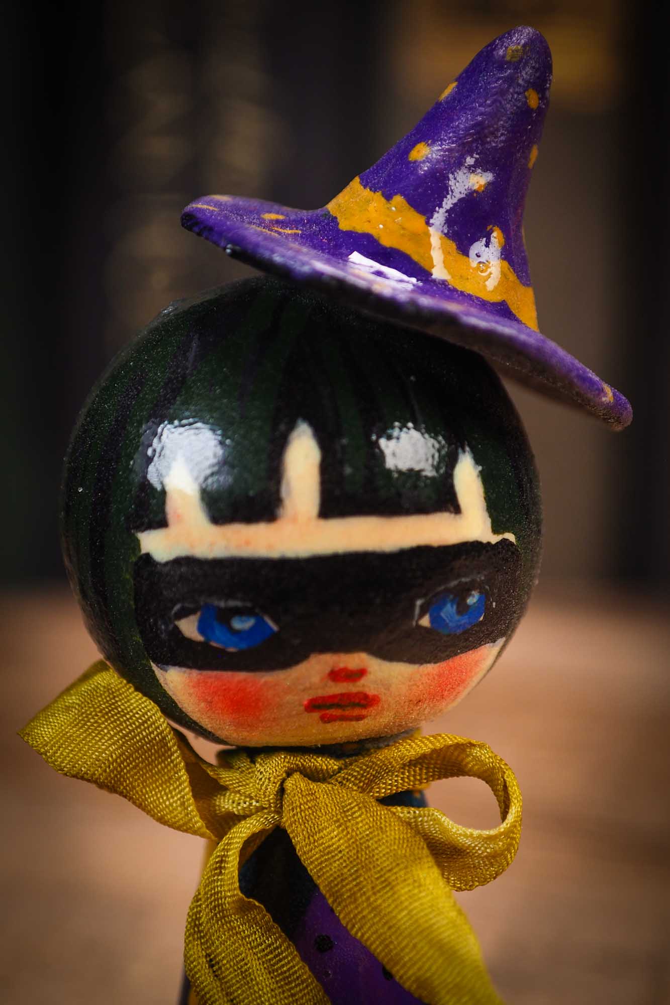 Small mini kokeshi Halloween art doll with black hair, purple witch hat, and yellow scarf, made by Idania Salcido, the artist behind Danita Art.