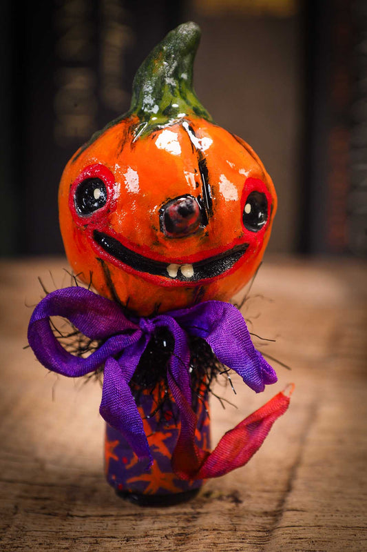 Small Halloween mini kokeshi art doll figurine with orange clay pumpkin head, orange and purple stars body, purple ribbon. Made by Idania Salcido, Danita Art.