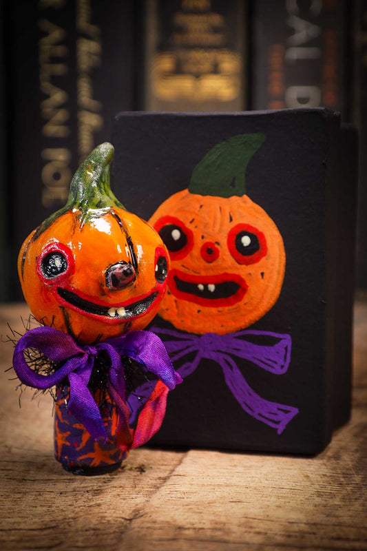 Small Halloween mini kokeshi art doll figurine with orange clay pumpkin head, orange and purple stars body, purple ribbon. Made by Idania Salcido, Danita Art.