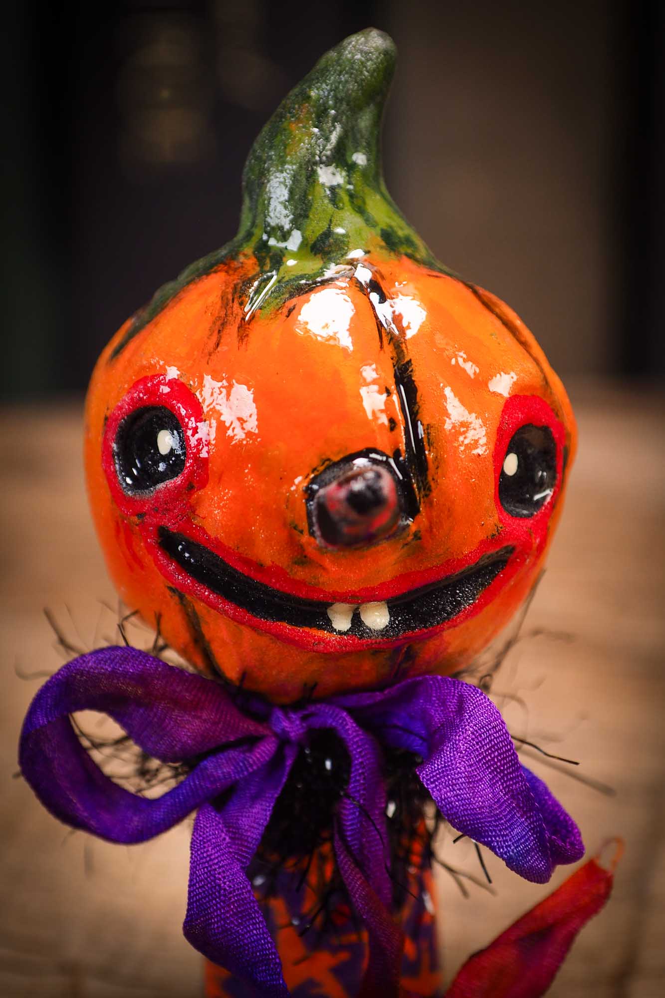 Small Halloween mini kokeshi art doll figurine with orange clay pumpkin head, orange and purple stars body, purple ribbon. Made by Idania Salcido, Danita Art.