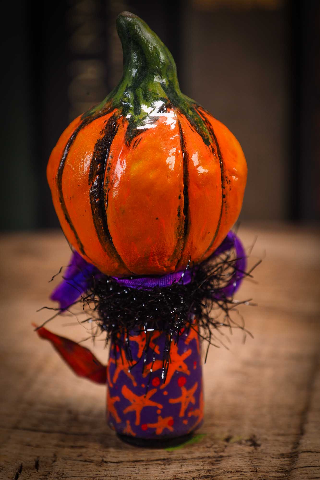 Small Halloween mini kokeshi art doll figurine with orange clay pumpkin head, orange and purple stars body, purple ribbon. Made by Idania Salcido, Danita Art.