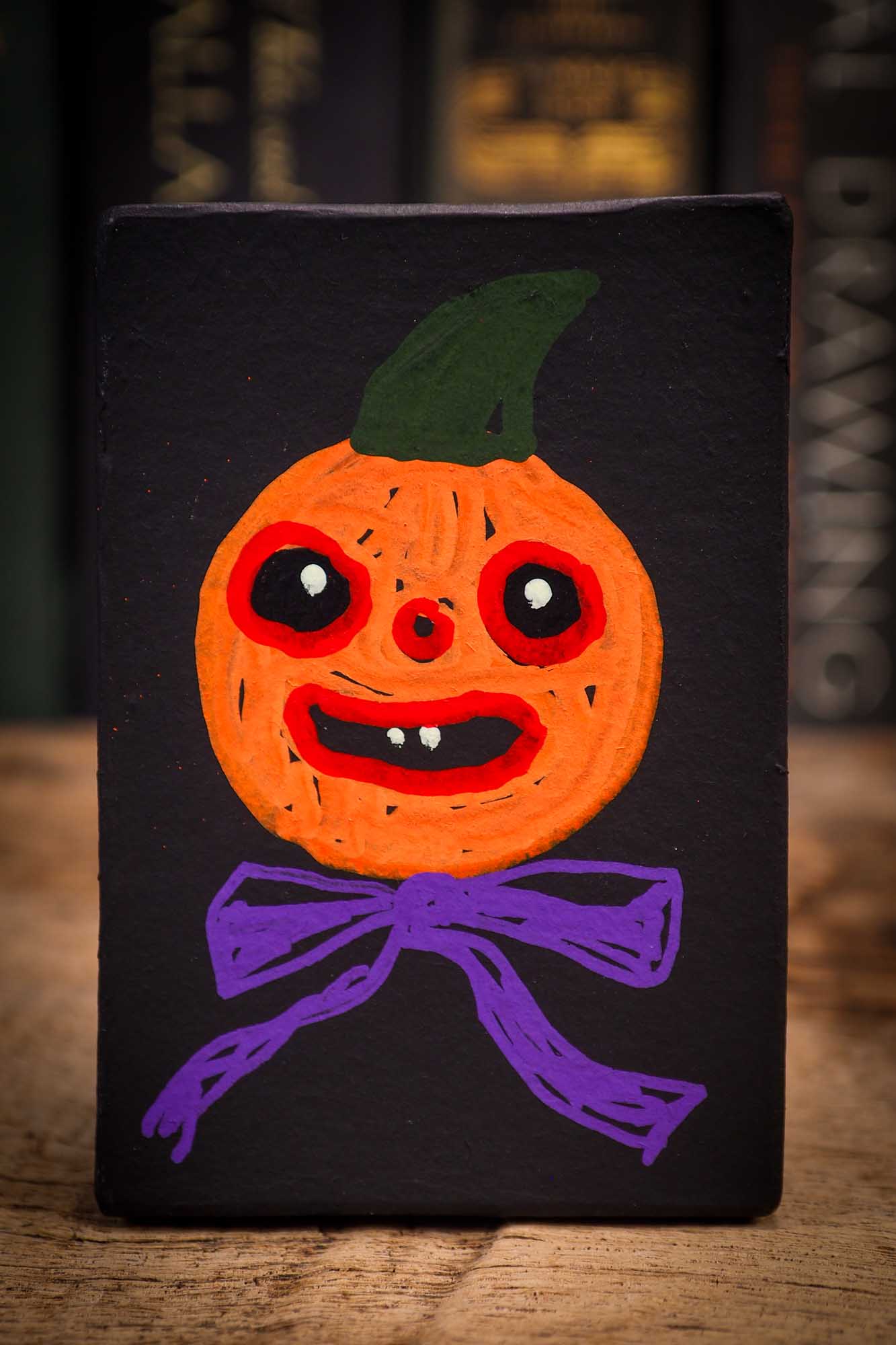 Small Halloween mini kokeshi art doll figurine with orange clay pumpkin head, orange and purple stars body, purple ribbon. Made by Idania Salcido, Danita Art.