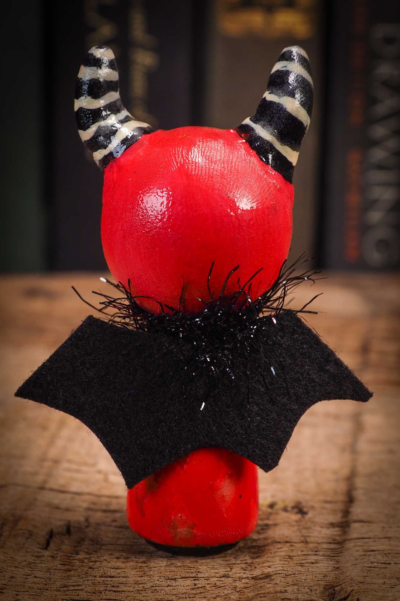 Small Halloween mini kokeshi art doll figurine with sculpted horned red devil head, striped horns, black wings and scarf. Made by Idania Salcido, Danita Art.