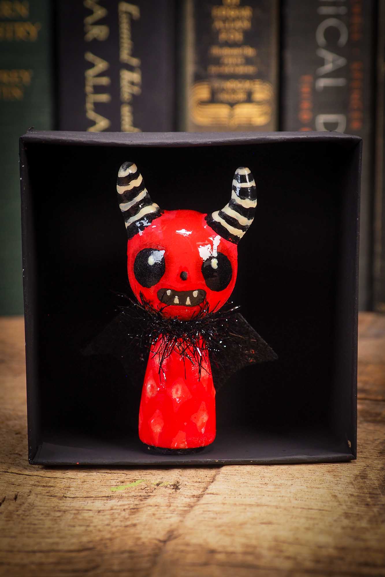 Small Halloween mini kokeshi art doll figurine with sculpted horned red devil head, striped horns, black wings and scarf. Made by Idania Salcido, Danita Art.