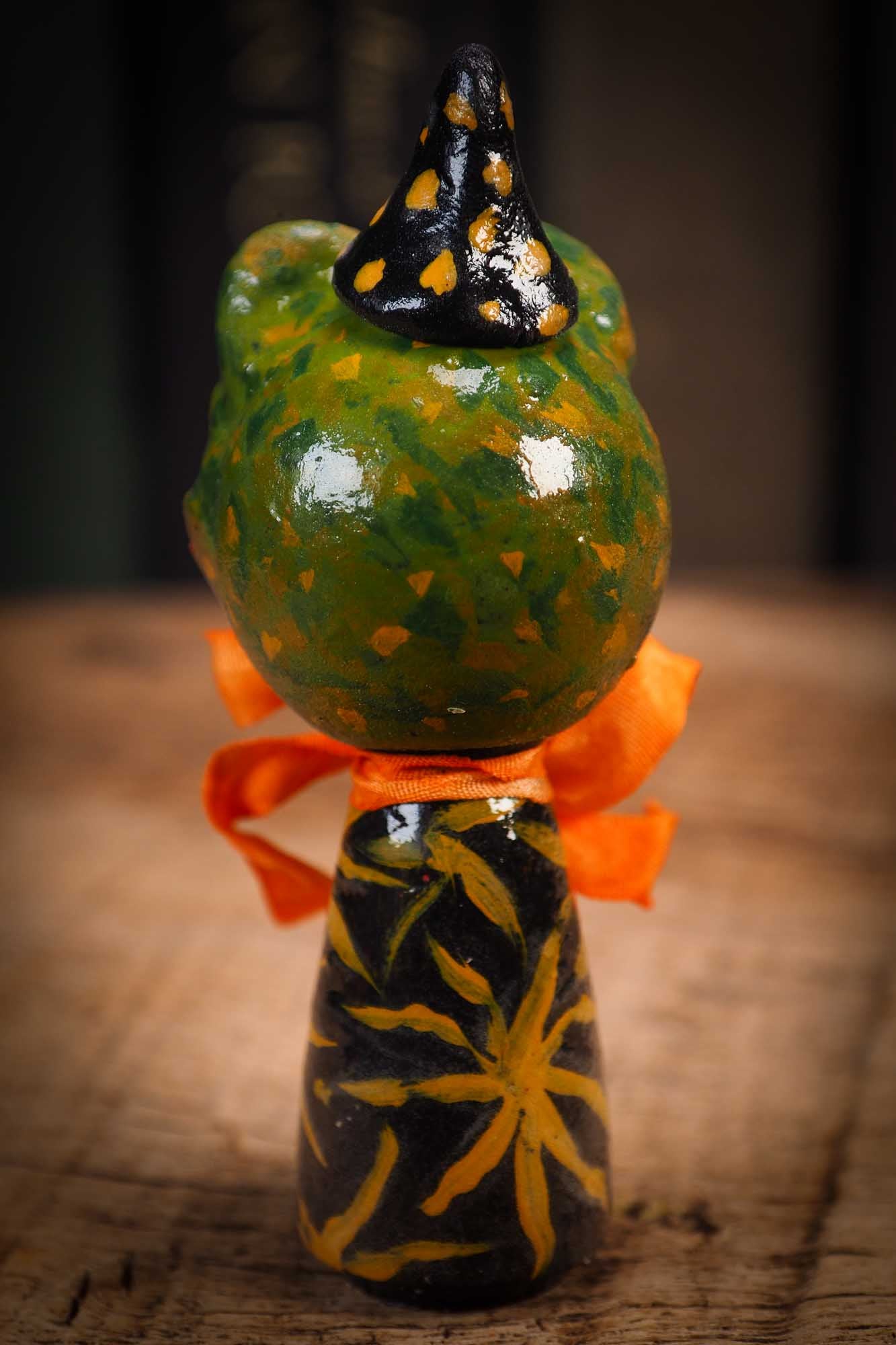 Small Halloween mini kokeshi art doll magic green toad wizard figurine with painted star body, orange silk bow. Made by Idania Salcido, Danita Art.