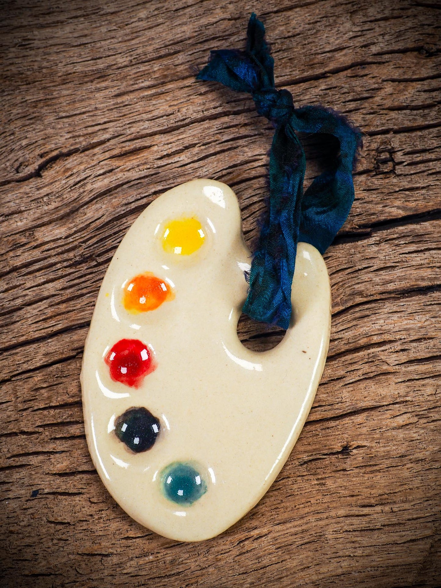 Handmade ceramic mini painter’s palette ornament with colorful paint wells, ideal as an artist gift or Christmas decoration by Idania Salcido Danita Art.