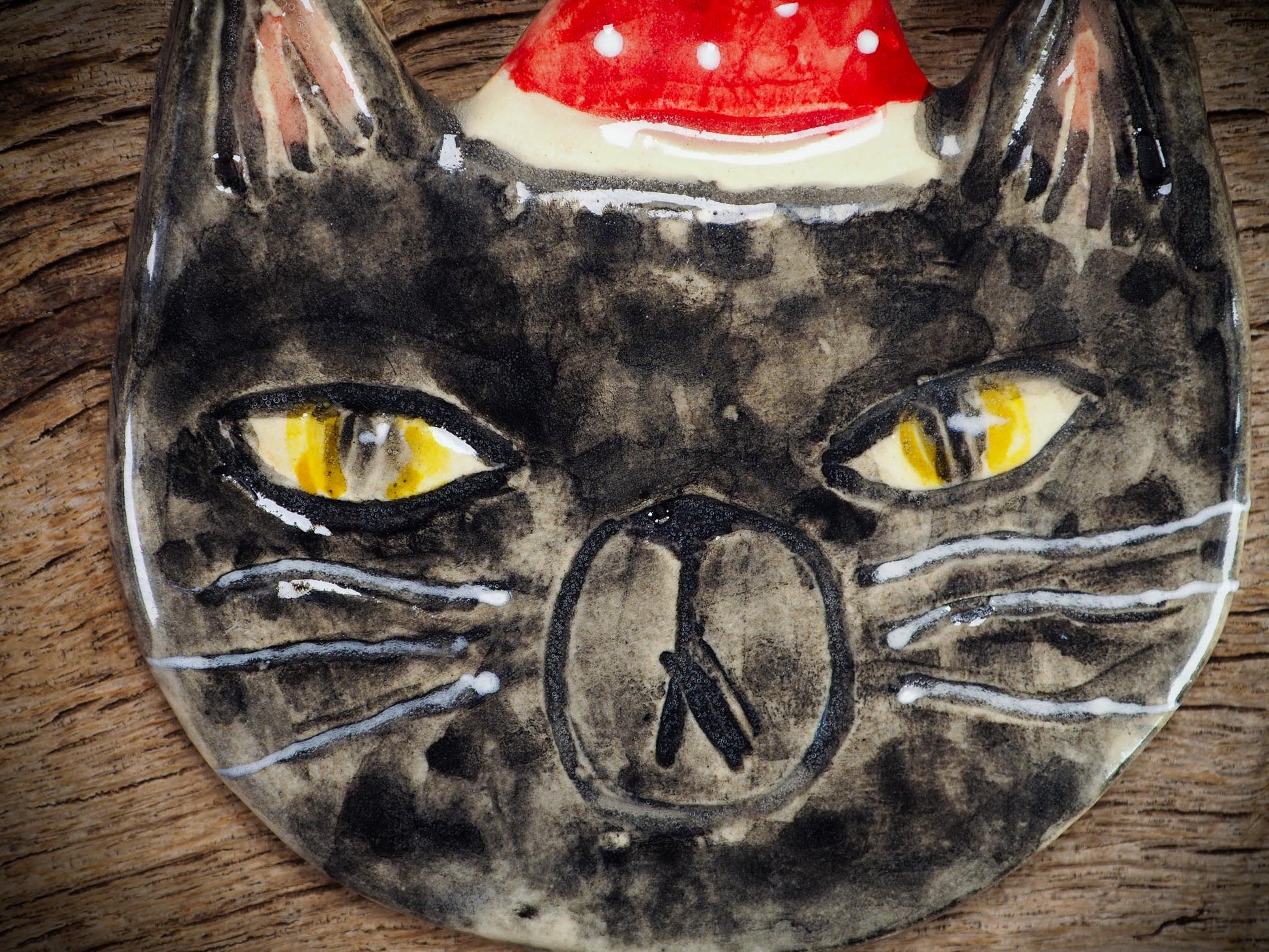 Handmade ceramic black cat ornament named Loki with red holiday hat and ribbon, created by Danita Art Idania Salcido for Christmas decorating or gifting.