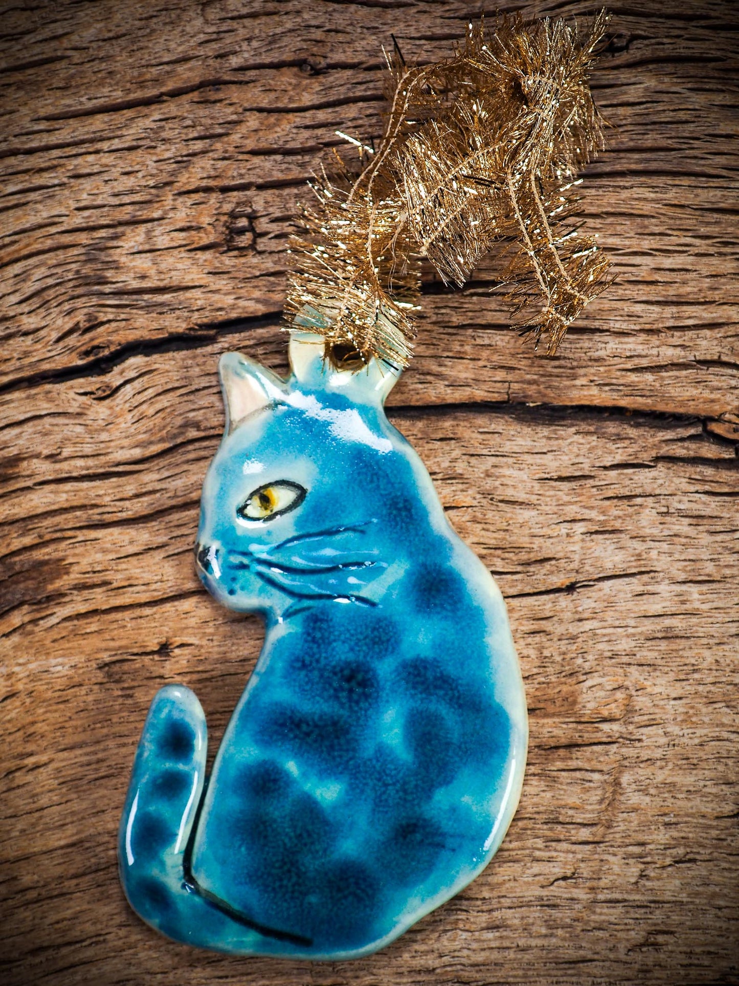 Handmade ceramic blue cat ornament with painted face and curled tail, created by Idania Salcido Danita Art for holiday decoration or gifting.