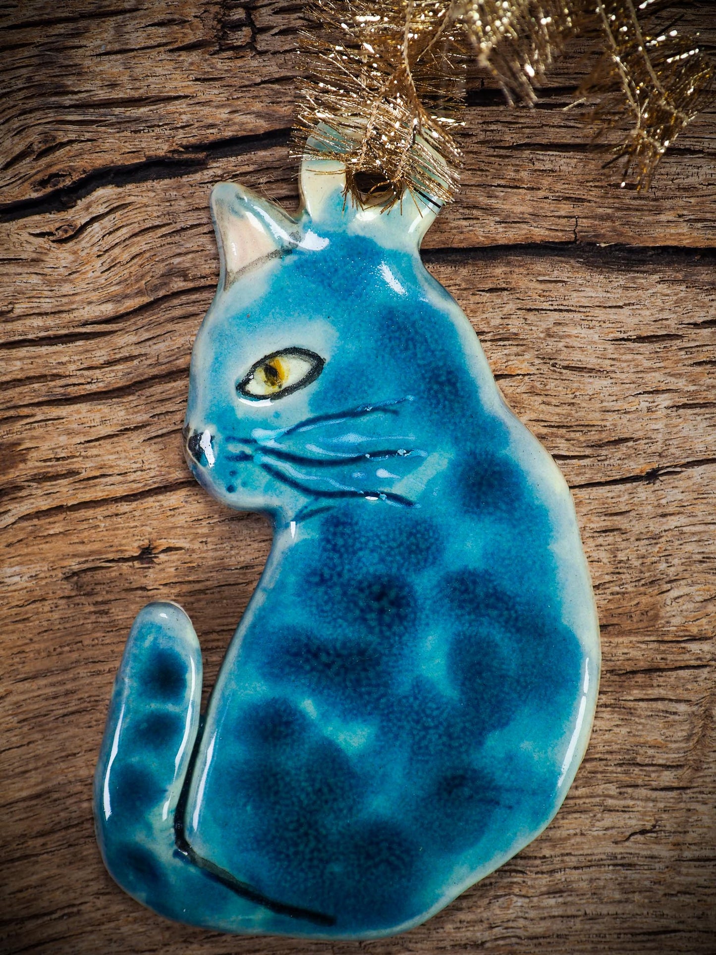 Handmade ceramic blue cat ornament with painted face and curled tail, created by Idania Salcido Danita Art for holiday decoration or gifting.