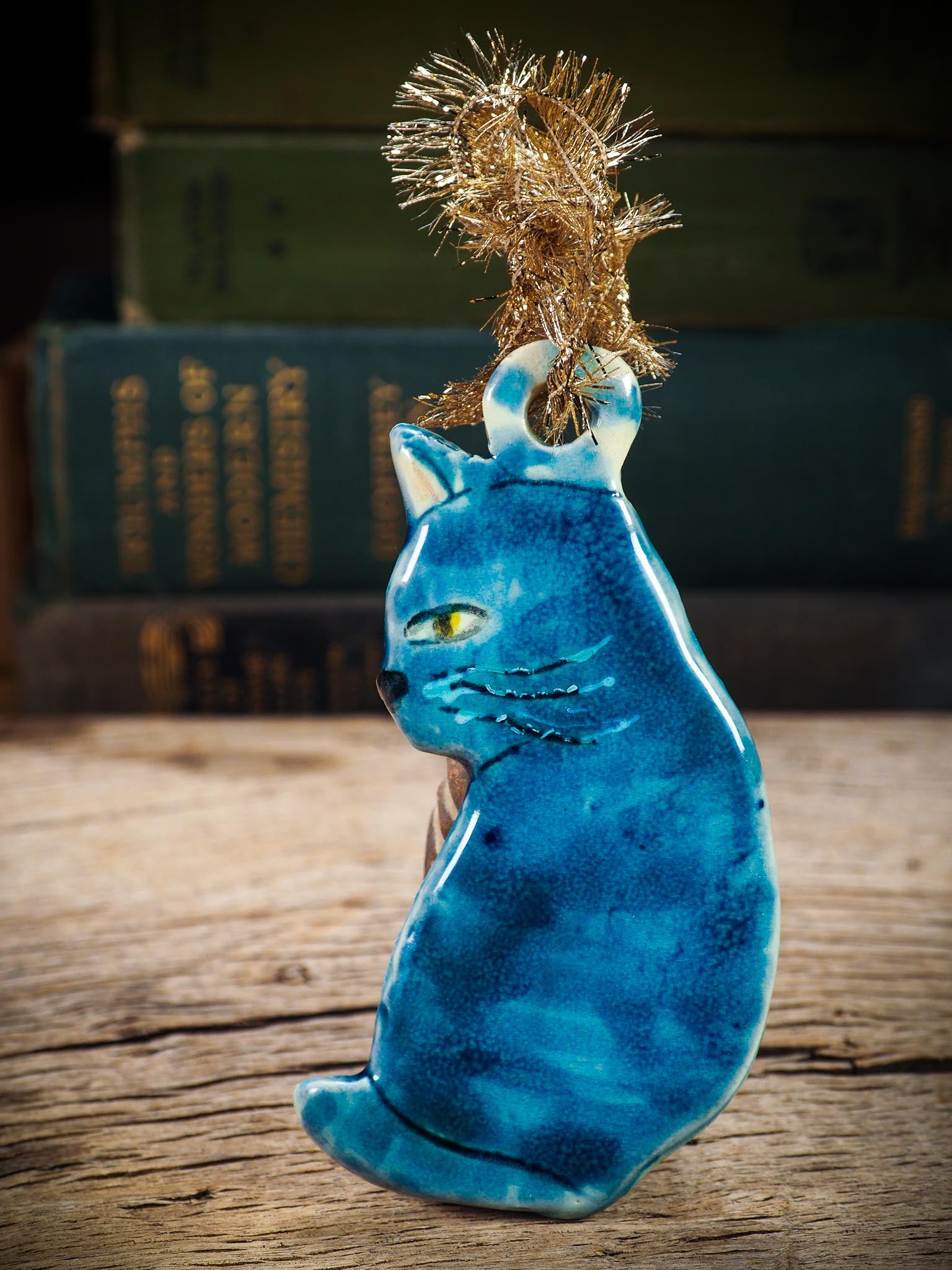 Handmade ceramic blue cat ornament with painted face and curled tail, created by Idania Salcido Danita Art for holiday decoration or gifting.