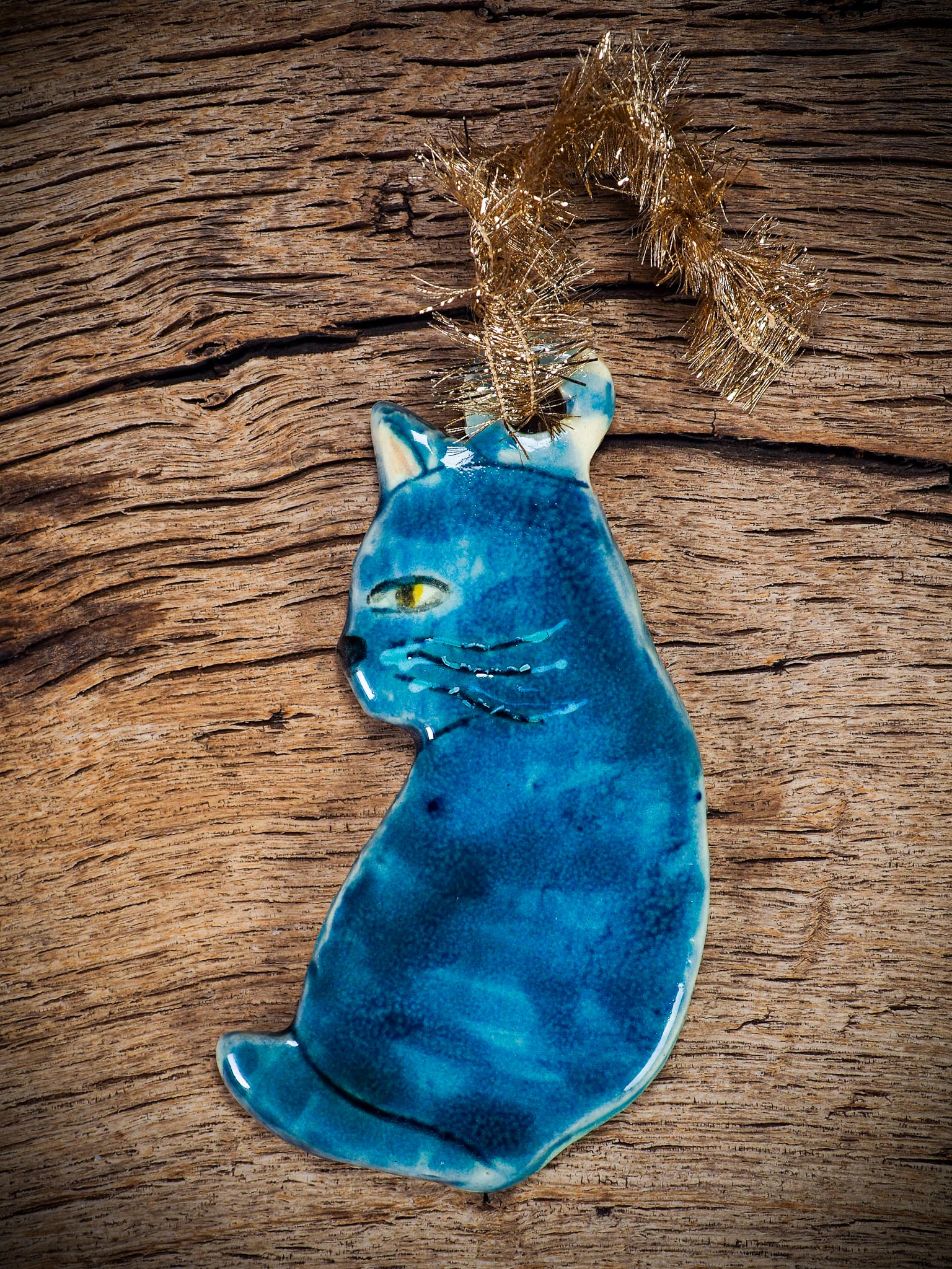 Handmade ceramic blue cat ornament with painted face and curled tail, created by Idania Salcido Danita Art for holiday decoration or gifting.