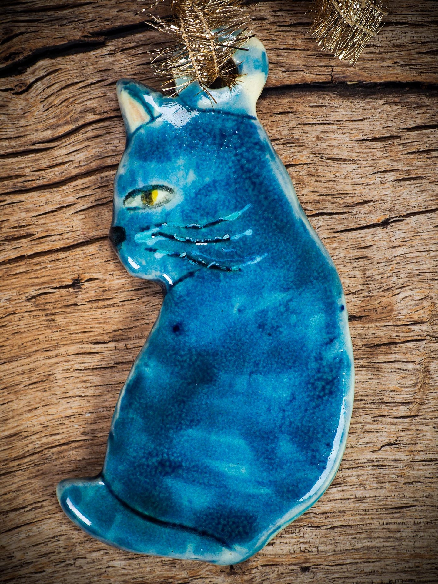 Handmade ceramic blue cat ornament with painted face and curled tail, created by Idania Salcido Danita Art for holiday decoration or gifting.