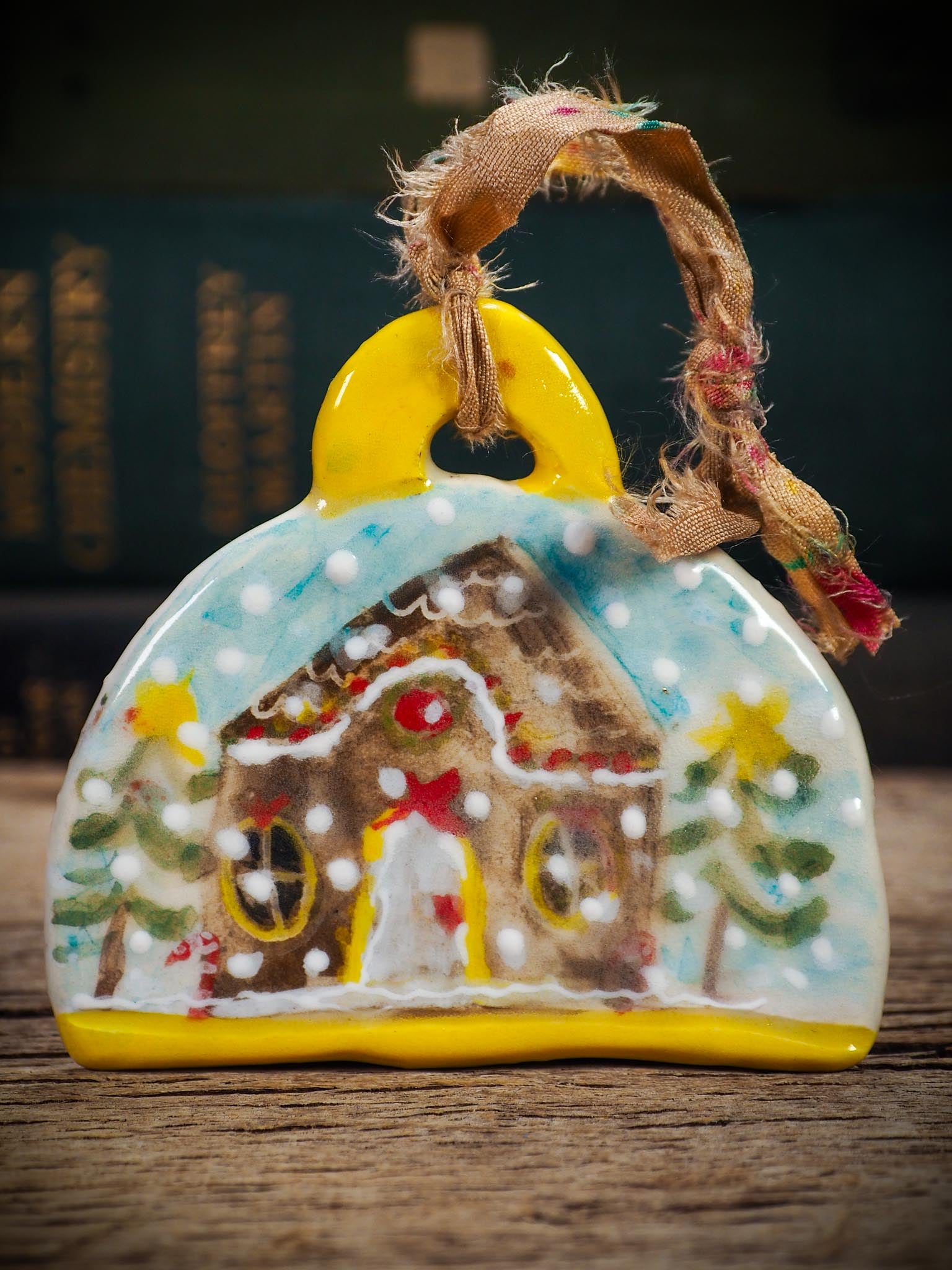Handmade ceramic gingerbread house ornament with snowy details and ribbon, created by Idania Salcido Danita Art for Christmas decorating or gifting.