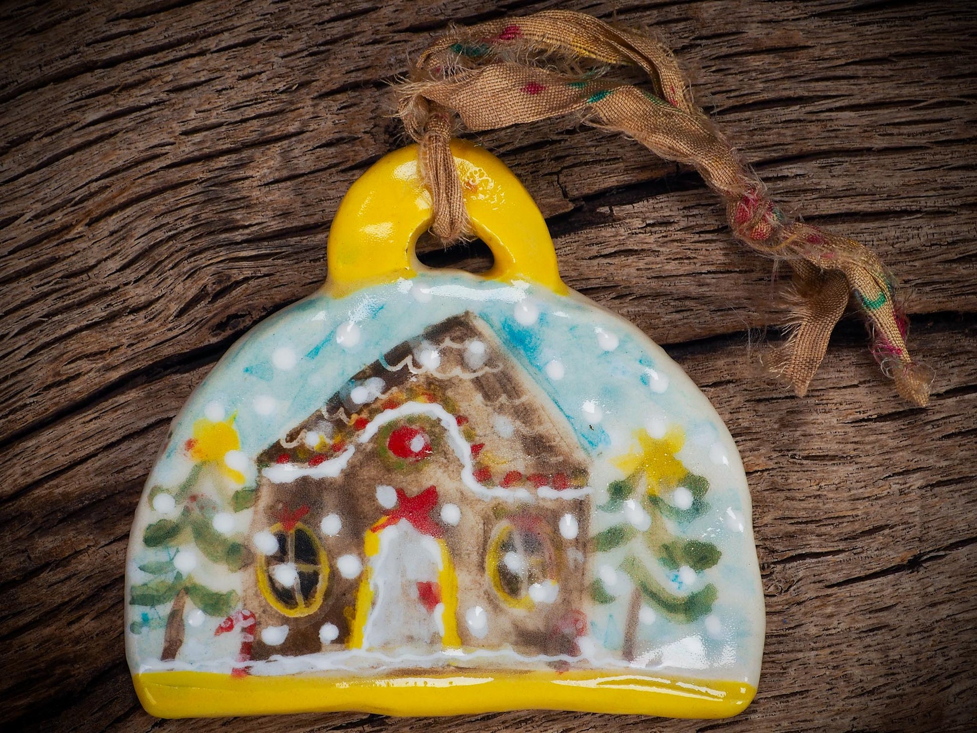 Handmade ceramic gingerbread house ornament with snowy details and ribbon, created by Idania Salcido Danita Art for Christmas decorating or gifting.