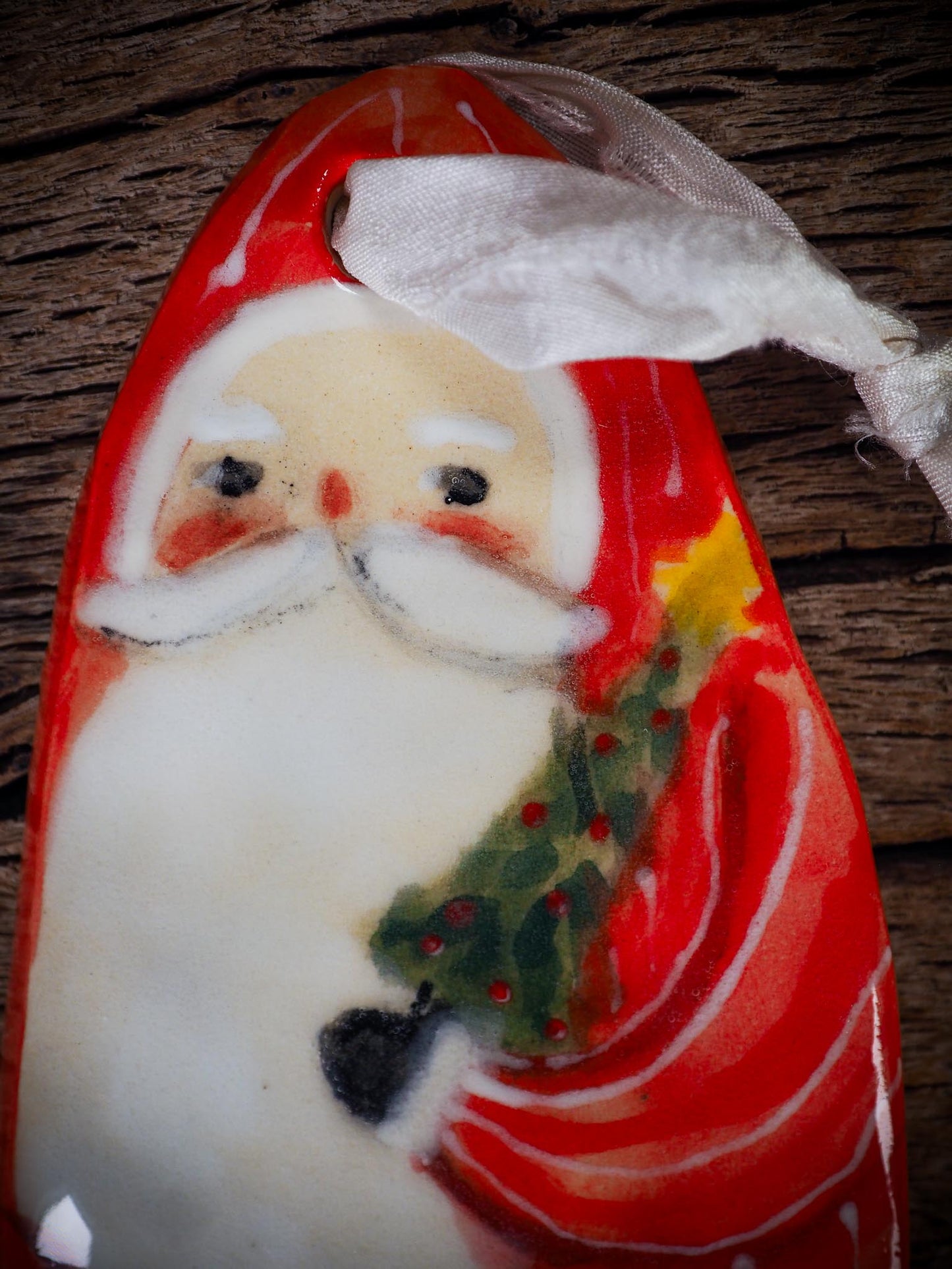 Handmade ceramic Santa figure ornament with red coat and ribbon, created by Danita Art for Christmas decoration or gifting. 
