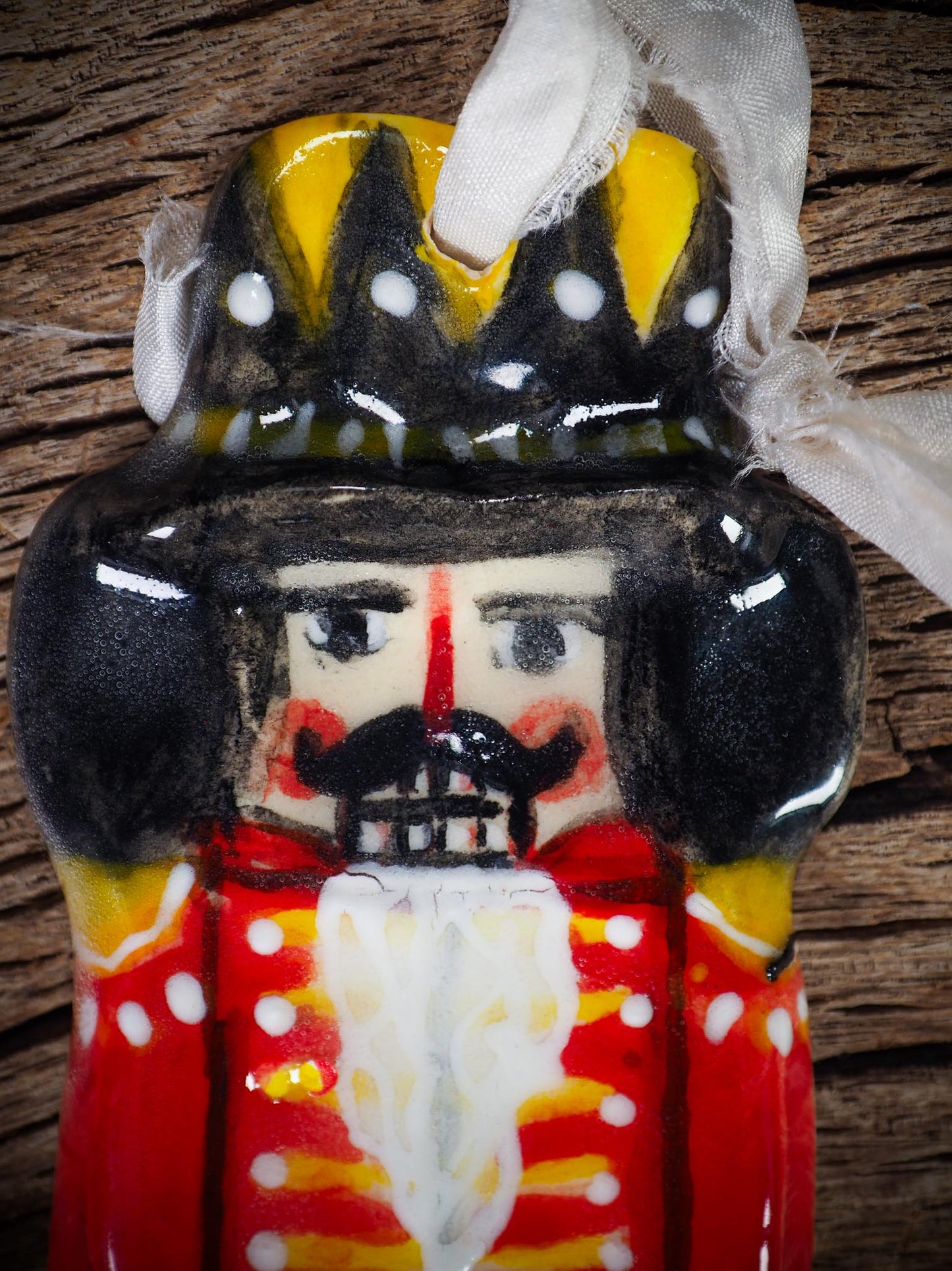 Handmade ceramic nutcracker ornament with red uniform and ribbon, created by Idania Salcido Danita Art for Christmas decoration or gifting.